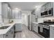 Modern kitchen featuring gray cabinets, stainless steel appliances, and white countertops at 4270 Defoe St, Strasburg, CO 80136