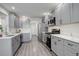 Modern kitchen with gray cabinets, stainless steel appliances, white quartz countertops, and gray wood-look flooring at 4270 Defoe St, Strasburg, CO 80136