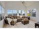 Bright living room features large windows, vaulted ceiling, ceiling fan, and a comfortable brown sectional sofa at 4270 Defoe St, Strasburg, CO 80136