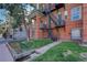 This shows the side of the brick apartment building, including the fire escape, trees, and landscaping at 1376 N Pearl St # B1, Denver, CO 80203