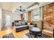 Comfortable living room featuring exposed brick, hardwood floors, a gray couch and oversized windows at 1376 N Pearl St # B1, Denver, CO 80203