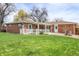Well-maintained backyard featuring a grassy lawn, mature trees, and a covered patio at 375 Kohl St, Broomfield, CO 80020