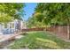 The backyard boasts a green lawn, mature trees, and a cozy patio with an umbrella-covered dining table at 1540 Meachum Way, Erie, CO 80516