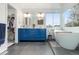 Stylish primary bathroom with blue vanity, soaking tub, and a walk-in closet at 1540 Meachum Way, Erie, CO 80516