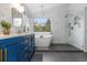 Stylish primary bathroom features soaking tub, shower, blue vanity and bright windows at 1540 Meachum Way, Erie, CO 80516