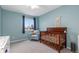 Cozy Bedroom with blue walls, wood crib, and plush seating area at 1540 Meachum Way, Erie, CO 80516