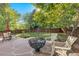 Backyard patio features stone pavers, a modern fire pit, Adirondack chairs, and ambient string lights at 1540 Meachum Way, Erie, CO 80516