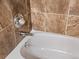 Close-up of white bathtub with chrome fixtures and brown-tiled walls at 2800 Kalmia Ave # A310, Boulder, CO 80301