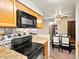 Functional kitchen featuring oak cabinets, black appliances, and an open layout to the dining area at 2800 Kalmia Ave # A310, Boulder, CO 80301