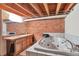 Unique bathroom featuring a jacuzzi tub, brick wall, open ceiling with exposed pipes, and a double vanity at 1143 Auraria Pkwy # 101, Denver, CO 80204