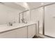 Bathroom with double sinks, quartz countertops, and a glass-enclosed shower at 15261 Fillmore St, Thornton, CO 80602