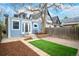Charming backyard with artificial turf, brick patio, and blue siding on house with French doors at 161 W Maple Ave, Denver, CO 80223
