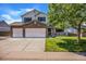 Daytime view of a charming two-story home featuring a stone-accented facade, a well-manicured lawn, and a three-car garage at 1325 Kingsfield St, Castle Rock, CO 80104