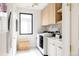 Efficient laundry room with built-in storage, window, washer, dryer, and white countertops for folding and sorting at 1130 S Cook St, Denver, CO 80210