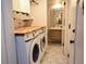Functional laundry room features modern washer/dryer, butcher block countertop, storage shelves, and convenient access to the bathroom at 8229 Estes Ct, Arvada, CO 80005