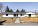 Charming single-story home with a modern white exterior, black trim, and a well-manicured front yard at 11825 W 25Th Ave, Lakewood, CO 80215