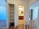 Hallway with an open closet with multiple shelves and access to a bathroom at 10561 W Dartmouth Ave, Lakewood, CO 80227