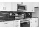 This kitchen features white cabinets, black hardware, and a black marble backsplash at 6519 Pinewood Dr, Parker, CO 80134