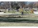 A playground with swings, a slide, and wooden posts for climbing, all set on a grassy area with walking paths at 832 S Gilpin St, Denver, CO 80209