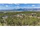 An aerial view of the house nestled among the green foliage with mountains in the distance at 17575 Minglewood Trl, Monument, CO 80132