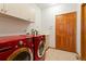 A laundry room featuring red washer and dryer units, complemented by overhead cabinets and a tiled floor at 17575 Minglewood Trl, Monument, CO 80132