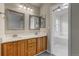 Bathroom featuring dual sinks, wood cabinets, and access to a separate tub and shower area at 6735 W 97Th Cir, Westminster, CO 80021