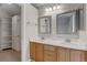 Bathroom featuring dual sinks, wood cabinets, and access to a closet space at 6735 W 97Th Cir, Westminster, CO 80021