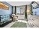 Charming Bedroom featuring a crib, glider, and a dresser, creating a cozy and inviting atmosphere at 12978 Dexter St, Thornton, CO 80241