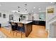 Open kitchen with a large island featuring bar seating, stainless steel appliances, and hardwood floors for a seamless flow at 12978 Dexter St, Thornton, CO 80241