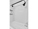 White tiled shower with black fixtures and practical storage shelves at 12978 Dexter St, Thornton, CO 80241