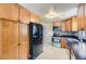 Efficient kitchen with wooden cabinets, black appliances, and mosaic backsplash at 10633 E 6Th Pl, Aurora, CO 80010