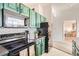 Bright kitchen featuring black appliances, black countertops and green painted cabinets at 15475 Andrews Dr # 318, Denver, CO 80239