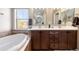 Bright bathroom featuring a soaking tub, dual sink vanity, and a window with a beautiful view at 9186 Viaggio Way, Highlands Ranch, CO 80126