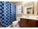 Cozy bathroom featuring a shower with a blue patterned curtain, a toilet, and a wood vanity at 9186 Viaggio Way, Highlands Ranch, CO 80126