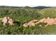 Aerial perspective of estate nestled amongst trees and rock formations, offering privacy and scenic views at 3755 N Rampart Range Rd, Littleton, CO 80125