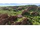 Stunning aerial view of luxury home nestled among red rock formations and lush greenery at 3755 N Rampart Range Rd, Littleton, CO 80125