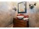 Powder room featuring a wood vanity, vessel sink, ornate mirror, and sconce lighting at 3755 N Rampart Range Rd, Littleton, CO 80125