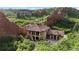 Stunning aerial view featuring a grand estate with tiled roof nestled between red rock formations at 3755 N Rampart Range Rd, Littleton, CO 80125