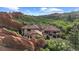 Exterior view of a luxury home with red rock formations and lush greenery in the background at 3755 N Rampart Range Rd, Littleton, CO 80125