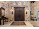 Stone foyer with antique door, ornate wall sconces, stone walls, and decorative mirror, creating a castle-like entrance at 3755 N Rampart Range Rd, Littleton, CO 80125