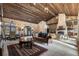 Spacious living room with stone walls, wooden ceiling, stone fireplace and luxury furniture at 3755 N Rampart Range Rd, Littleton, CO 80125