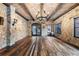 Open living room with hardwood floors, stone walls, chandelier, and large windows providing natural light at 3755 N Rampart Range Rd, Littleton, CO 80125