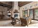 Living room with stone fireplace, exposed beams, rustic furniture, and french doors offering natural light at 3755 N Rampart Range Rd, Littleton, CO 80125