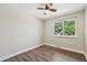 Cozy bedroom with wood-look floors, a ceiling fan, and a window overlooking green trees at 7862 W 84Th Ct, Arvada, CO 80005