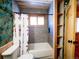 View of the bathroom showcasing the tub/shower with window, rustic wood ceiling, and built-in wall shelving at 750 Cougar Dr, Boulder, CO 80302