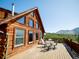Spacious wooden deck with table and chairs, attached to a log cabin with scenic mountain views and blue skies at 750 Cougar Dr, Boulder, CO 80302