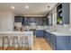 Well-lit kitchen featuring navy blue cabinets, stainless steel appliances, an island with a white countertop, and bar stool seating at 3937 Osceola St, Denver, CO 80212