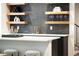 Stylish wet bar with floating shelves, wine storage, elegant glassware, and modern faucet against a textured tile backsplash at 1466 S Gaylord St, Denver, CO 80210