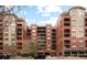 Multi-story red brick building with balconies, roof decks, and ground-level retail spaces at 1975 N Grant St # 617, Denver, CO 80203