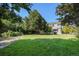 A spacious grassy backyard with mature trees and landscaping surrounding a two-story gray house at 5405 Military Trl, Parker, CO 80134